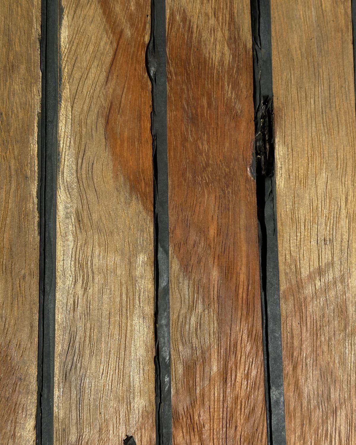 Detalj vremenskim utjecajima istrošenih letvica od tikovine i crnih fuga